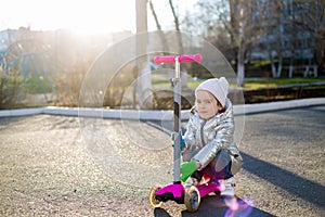 Little girl riding a scooter in the Park on a Sunny spring day. Active leisure and outdoor sport for children