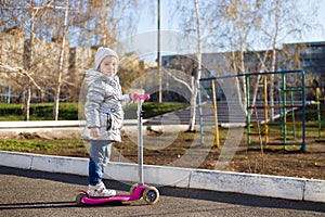 Little girl riding a scooter in the Park on a Sunny spring day. Active leisure and outdoor sport for children