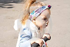 Little girl riding a scooter in the park way. Baby girl driving small scooter outdoors.Slow down, Kids play on the road