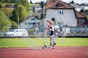 Little girl riding a scooter on a sports facility