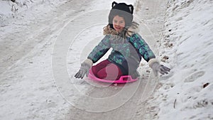 Little girl riding snow slides rolling down the hills, winter time winter holidays