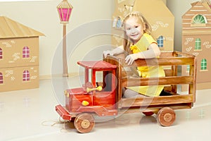 little girl is riding a toy wooden car.