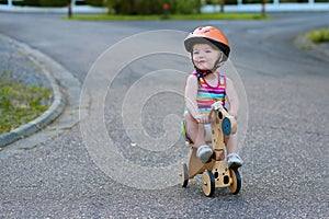 Little girl riding wooden tricycle on the street