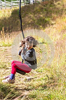 Girl riding zip-line in overgrown playground.