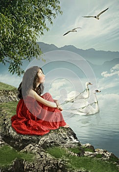 Little girl by the river and swans