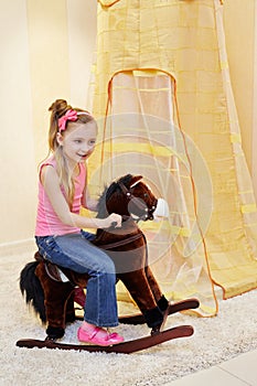 Little girl rocks on hobbyhorse