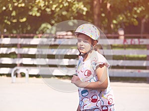 Little girl on roller skates in helmet at a park summer