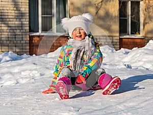 Little girl is rolling down the snow slide