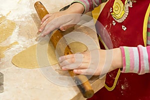 Little girl rolls out the dough