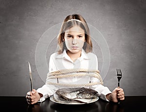 Little girl roped sitting at table