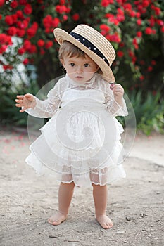 Little girl in rose garden next to a big bush of red roses