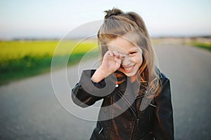 Little girl rubs her eyes with palm photo