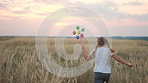 little girl run with a wind toy pinwheel. happy family kid dream concept. girl child run plays outdoors in the park