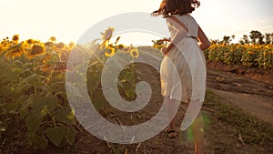 Little girl running across the field with sunflowers at sunset. slow motion video. girl runner in the field at sunset