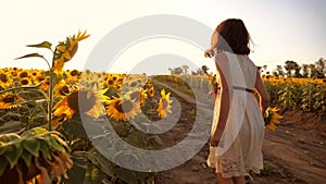 Little girl running across the field with sunflowers at sunset. slow motion video. girl runner in the field at sunset