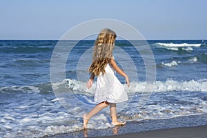 Little girl running beach in blue sea