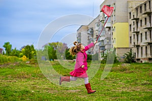 A little girl is running with butterfly net having fun