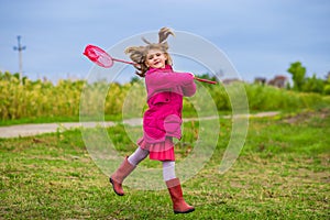A little girl is running with butterfly net having fun