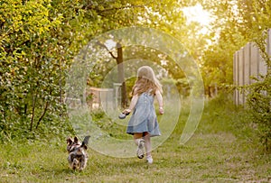 Little girl running with the dog in the countryside