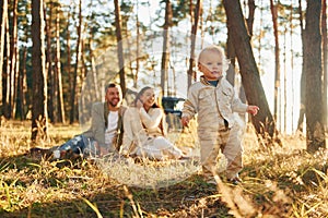 Little girl is running. Happy family of father, mother and little daughter is in the forest