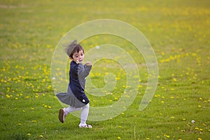 Little girl running on spring field full of dandelion