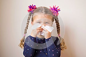The little girl with runny nose blows into handkerchief.
