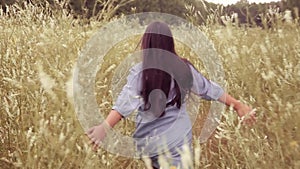 A Little girl runs across the field in the forest on a sunny day