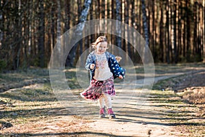 Little girl runs along a forest path