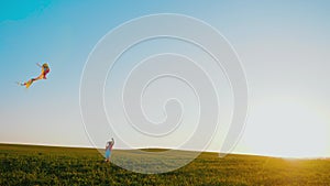 Little girl runs with kite through meadow, launch kite in air at golden sunset