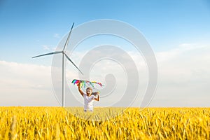 Little girl runs in a wheat field with a kite