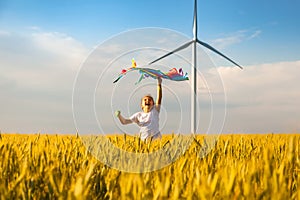 Little girl runs in a wheat field with a kite
