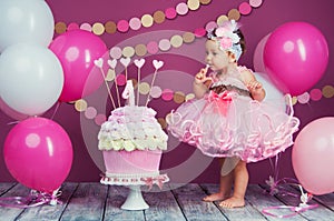The little girl`s birthday girl was smeared into a cake. The first cake. The use of the first cake. Smash cake.