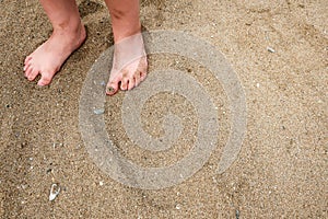 A little girl`s / child`s feet in the sand on a beach.