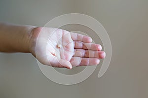 Little girl& x27;s hand holding and showing her fallen milk front tooth close up.