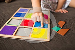 Little girl`s hands playing with a wood mosaic on a sofa. Educational games. Montessori Preschool early develop