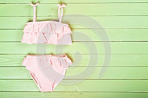 Little girl`s swimsuit on a wooden background. Top view. Space f