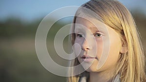 A little girl with a sad face looks forward