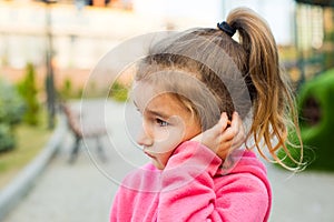 A little girl with a sad and frightened face holds her cheek with her hand - a tooth hurts. Ear pain, toothache, swollen cheek and