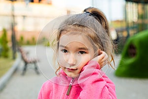 A little girl with a sad and frightened face holds her cheek with her hand - a tooth hurts. Ear pain, toothache, swollen cheek and