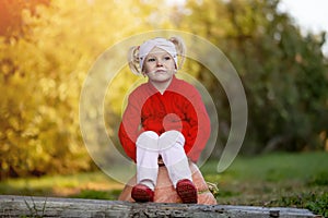 Little girl is sad while sitting on a pumpkin in the autumn garden