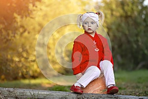 Little girl is sad while sitting on a pumpkin in the autumn garden