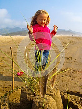 Little girl and sandcastle on sunny beach