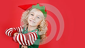 Little girl in Santa elf helper costume on bright red vivid color background