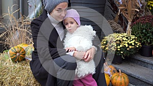 Little girl scared sitting with mom on the street Halloween with pumpkins on the background