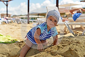 A little girl in a scarf playing on the sandy beach