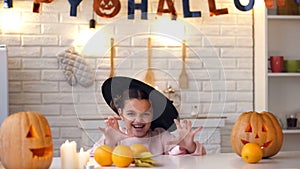 Little girl in scary witch costume trying to scare children, Halloween party