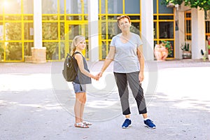 Little girl with school bag or satchel walking to school with grandmother.