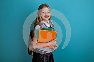 Little girl in a school dress standing isolated the blue background.