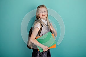 Little girl in a school dress standing isolated the blue background.