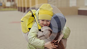 little girl schoolgirl with backpack runs hug her mother, kid rejoice over lessons, happy family, school bag behind back